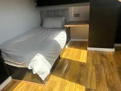 a bed in a small room with a wooden floor at Entire Seaside Home 6 Private Bedrooms Sleeps 10 in Wallasey
