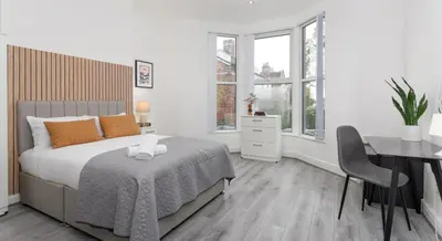 a bedroom with a bed and a desk and a table and chair at Residency apartments Sefton road in Walton on the Hill