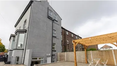 a building with a wooden pergola in front of it at Residency apartments Sefton road in Walton on the Hill