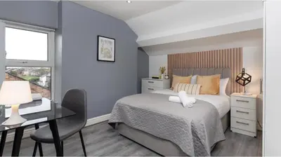 a bedroom with a bed and a desk and a window at Residency apartments Sefton road in Walton on the Hill