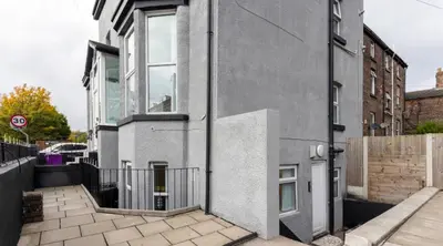 a gray building with a gate on the side of it at Residency apartments Sefton road in Walton on the Hill