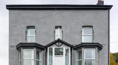 a gray house with white windows and a door at Residency apartments Sefton road in Walton on the Hill