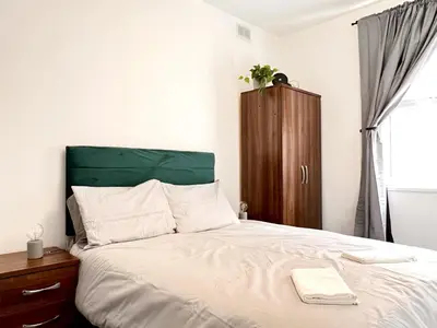 a bed with a green headboard and a wooden cabinet at Apartment 3 in Blackpool
