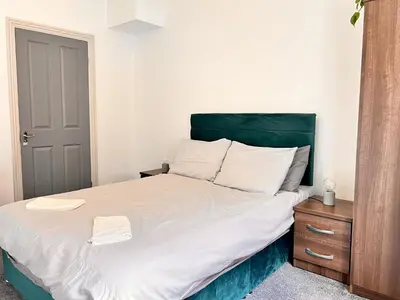 a bedroom with a large bed with a green headboard at Apartment 3 in Blackpool