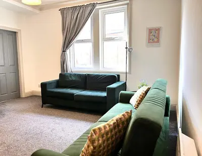 a living room with a green couch and a window at Apartment 3 in Blackpool