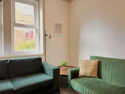 a living room with a green couch and a chair at Apartment 3 in Blackpool