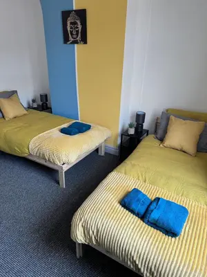 two beds in a room with blue pillows on them at Modern Retreat Your Birkenhead Heaven, A Peaceful Getaway in Birkenhead