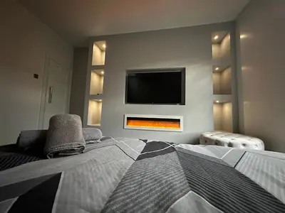 a bedroom with two beds and a tv on the wall at 3 BR- Central Wigan- HOT TUB in Ince-in-Makerfield