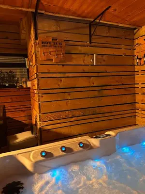 a bath tub in a room with a wooden wall at 3 BR- Central Wigan- HOT TUB in Ince-in-Makerfield