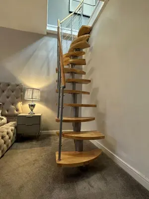 a wooden spiral staircase in a room with a couch at 3 BR- Central Wigan- HOT TUB in Ince-in-Makerfield