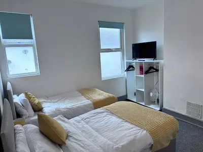 a bedroom with two beds and a flat screen tv at Stylish Retreat near Birkenhead & Liverpool Your Cozy Home Away From Home in Wallasey