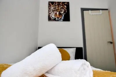 a pile of towels sitting on top of a bed at Stylish Retreat near Birkenhead & Liverpool Your Cozy Home Away From Home in Wallasey