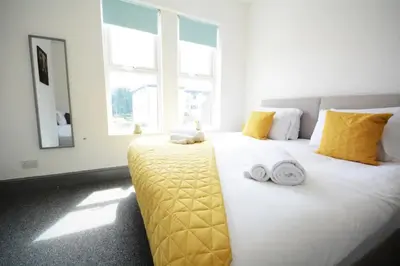 a bedroom with a large white bed with yellow pillows at Stylish Retreat near Birkenhead & Liverpool Your Cozy Home Away From Home in Wallasey