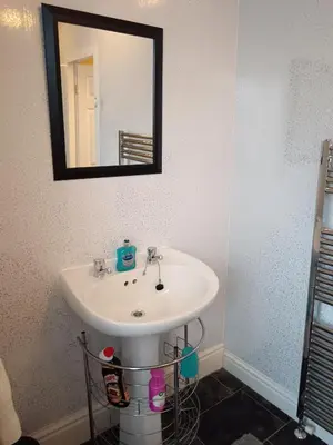 a bathroom with a white sink and a mirror at Heatherlea in Grange Over Sands