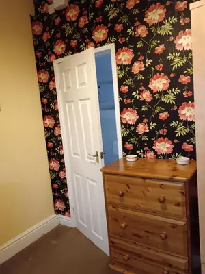 a bedroom with a dresser and a flower wallpaper at Heatherlea in Grange Over Sands