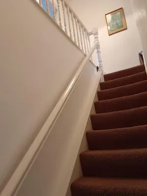 a staircase with brown carpeting and a stair case at Heatherlea in Grange Over Sands