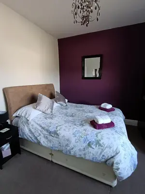 a bedroom with a large bed with a purple wall at Heatherlea in Grange Over Sands