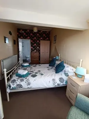 a bedroom with a large bed with blue pillows at Heatherlea in Grange Over Sands