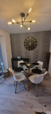 a dining room with a clock and a table and chairs at 3 bed home in Bolton Le Sands in Bolton le Sands
