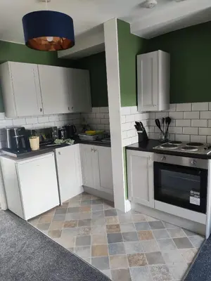 a kitchen with white appliances and green walls at The Old Bike Shop Flat 2 in Heapey