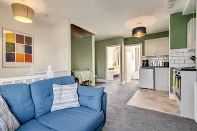 a living room with a blue couch and a kitchen at The Old Bike Shop Flat 2 in Heapey