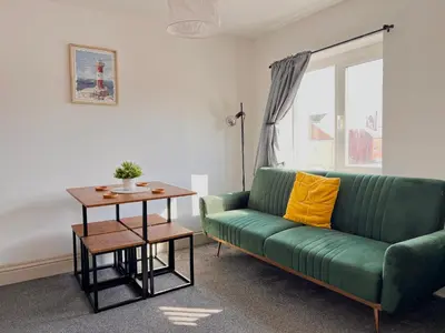 a living room with a green couch and a table at Apartment 6 in Blackpool