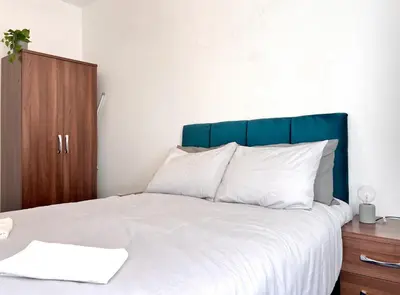 a bed with a blue headboard and white pillows at Apartment 6 in Blackpool