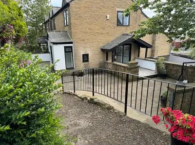 a black fence in front of a house at Sunshine cottage in Horwich