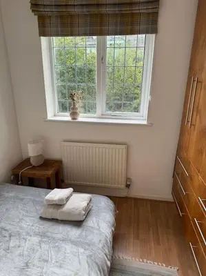 a bedroom with a bed and a large window at Sunshine cottage in Horwich
