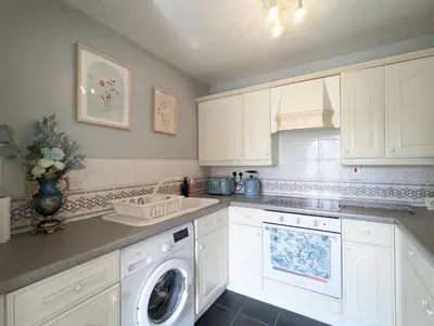 a kitchen with white cabinets and a washing machine at City Centre Vintage Theme Guest Rooms in Liverpool