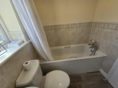 a bathroom with a tub and a toilet and a toilet paper roll at A Classic Home in Liverpool in Liverpool