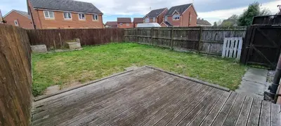 a backyard with a wooden fence and a yard with grass at A Classic Home in Liverpool in Liverpool