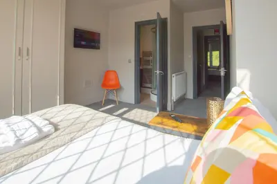 a bedroom with a bed and a orange chair at Parkside View Wallasey 5 bedroom 5 bathroom with on-street parking ideal for Groups Families or Contractors with vans by Rework Accommodation in Wallasey