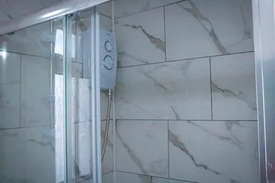 a shower in a bathroom with a marble wall at Anfield Walk in Liverpool