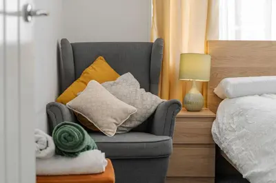 a gray chair with pillows sitting next to a bed at The Old Bike Cabin Flat 1 in Heapey