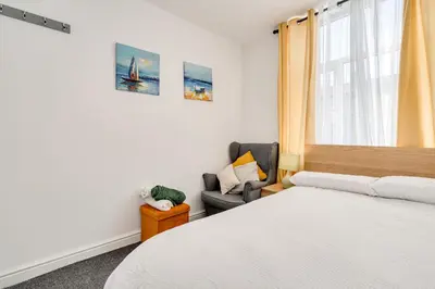 a bedroom with a bed and a chair and a window at The Old Bike Cabin Flat 1 in Heapey