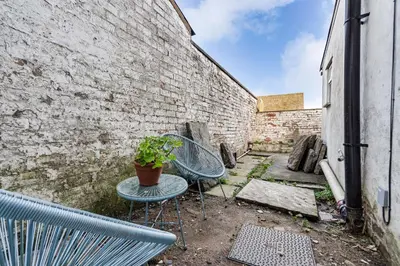 a patio with two chairs and a table with a potted plant at The Old Bike Cabin Flat 1 in Heapey