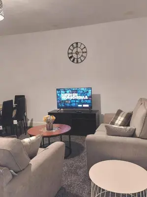 a living room with couches and a tv with a clock at Accrington - House - Sleeps 10 - Garden in Accrington