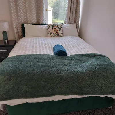 a bed with a green blanket with a hat on it at Accrington - House - Sleeps 10 - Garden in Accrington
