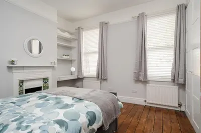 a bedroom with a bed and a fireplace and windows at Swiss Haven - Spacious 3 Bedroom House in Liverpool