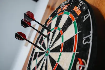 a dartboard with three darts in the middle at Swiss Haven - Spacious 3 Bedroom House in Liverpool