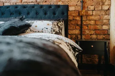 a bedroom with a black bed and a brick wall at Swiss Haven - Spacious 3 Bedroom House in Liverpool