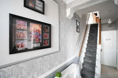 a hallway with a staircase with pictures on the wall at Swiss Haven - Spacious 3 Bedroom House in Liverpool