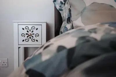 a bed with a pillow and an electrical outlet at Swiss Haven - Spacious 3 Bedroom House in Liverpool