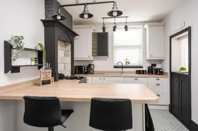 a kitchen with white cabinets and a black stove at Swiss Haven - Spacious 3 Bedroom House in Liverpool