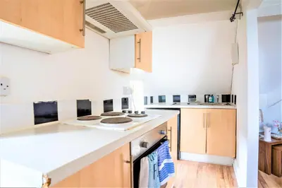 a kitchen with white counter tops and wooden cabinets at Travellers Stays In The Heart Of Orrell Park in Liverpool