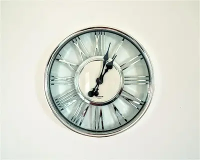 a silver clock is on a white wall at Travellers Stays In The Heart Of Orrell Park in Liverpool