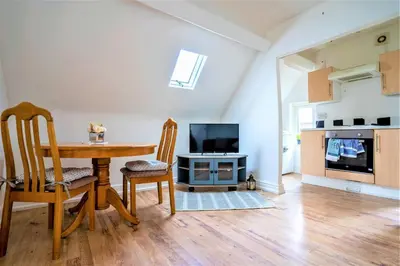 a living room with a dining room table and a television at Travellers Stays In The Heart Of Orrell Park in Liverpool