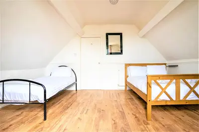 a bedroom with two beds and a wooden floor at Travellers Stays In The Heart Of Orrell Park in Liverpool