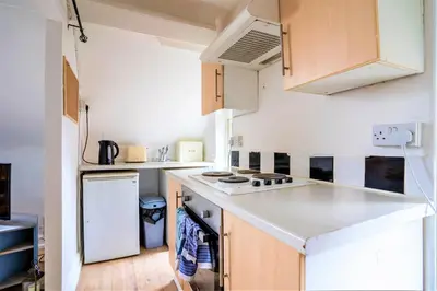 a small kitchen with white appliances and wooden cabinets at Travellers Stays In The Heart Of Orrell Park in Liverpool